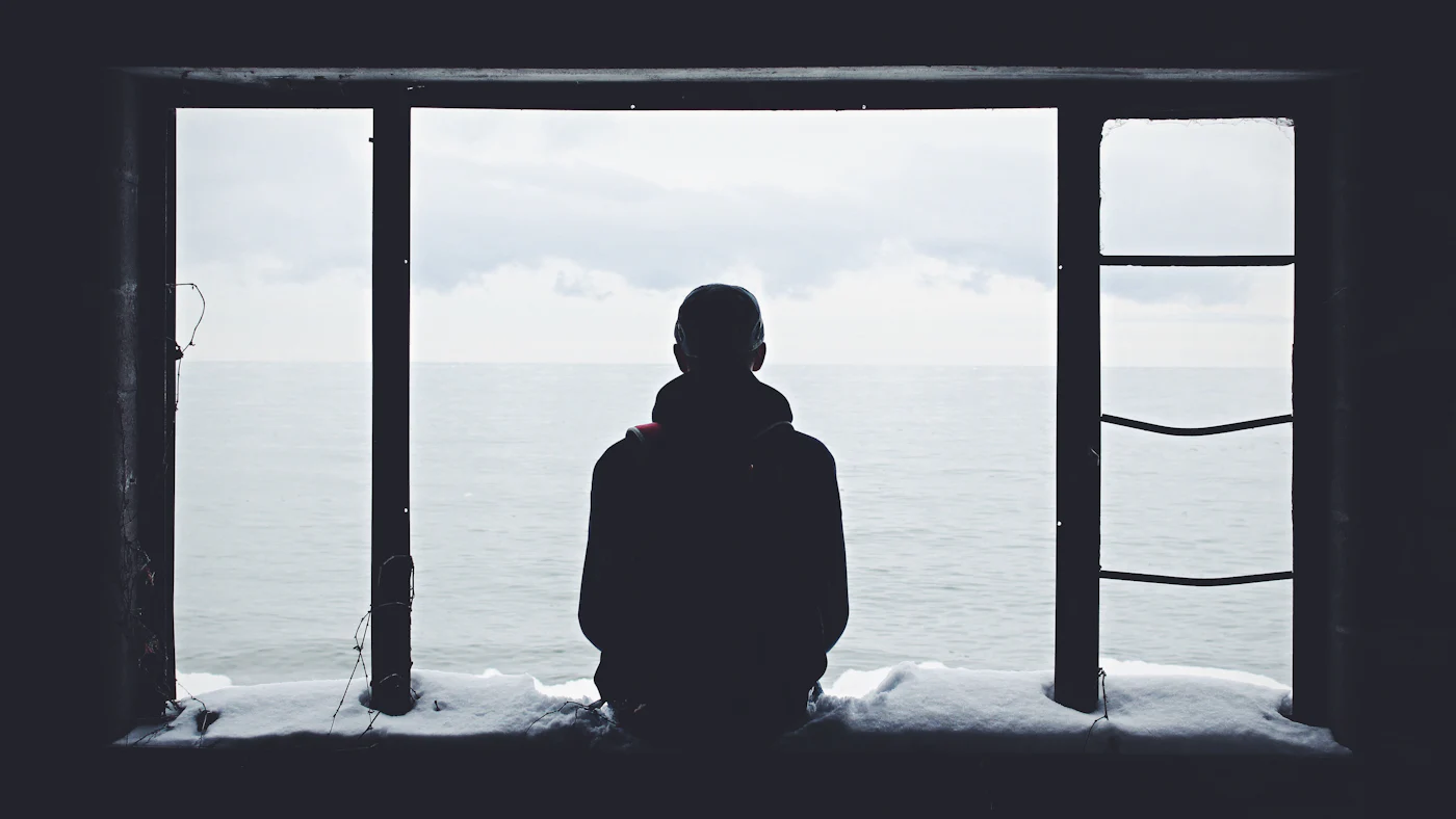 Eine Person steht als Silhouette vor einem großen Fenster